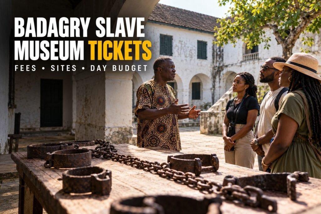 Guide talking to three visitors in front of an old whitewashed building, with iron shackles and chains laid out on a wooden table